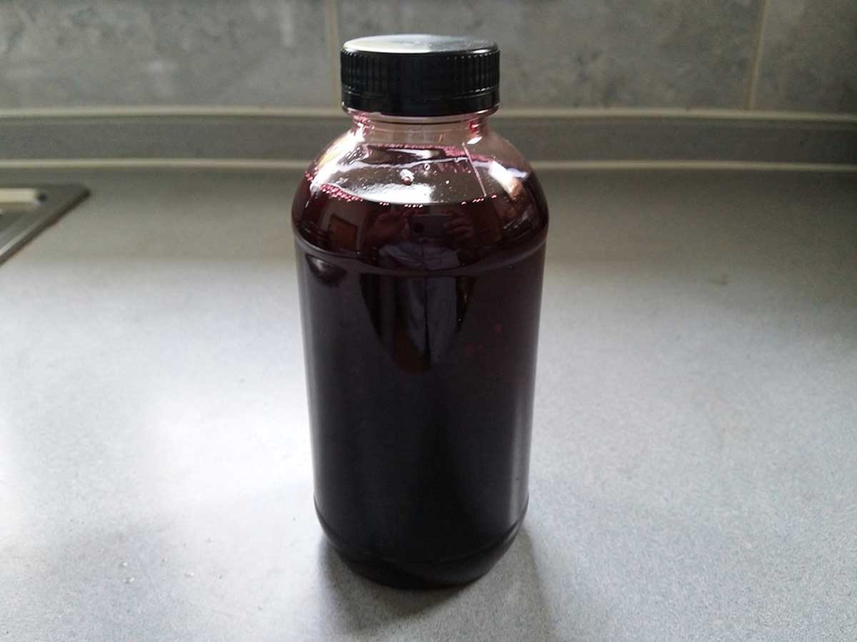 Een fles vol met vlierbessensiroop.