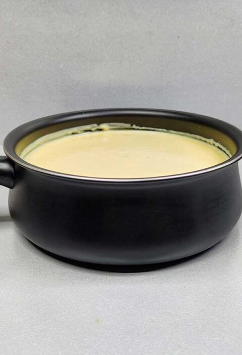 Een zwarte fonduepan met daarin kasfonue die opgewarmd moet worden.