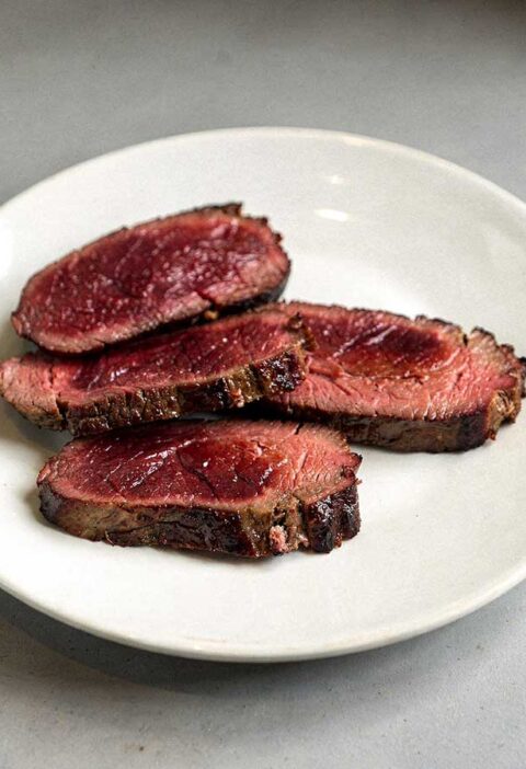 4 gebakken kangoeroes steaks op een wit bord.