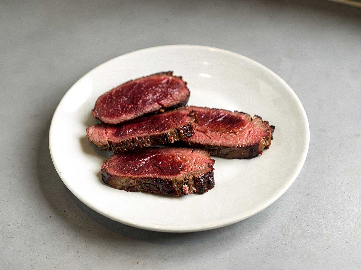 4 gebakken kangoeroes steaks op een wit bord.
