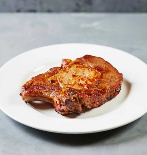 Een gebakken ribkarbonade op een wit bord.