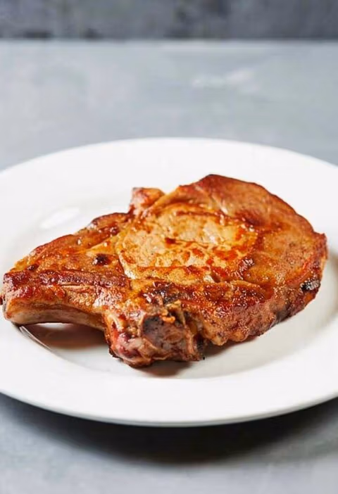 Een gebakken ribkarbonade op een wit bord.