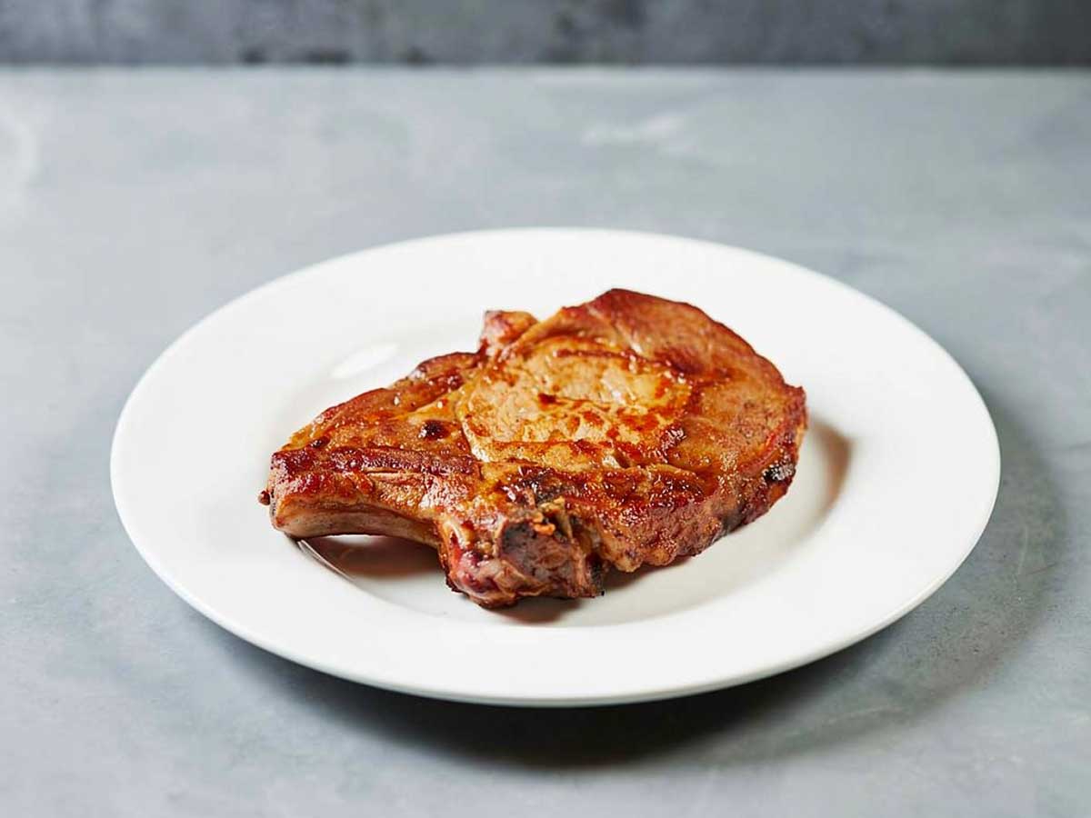 Een gebakken ribkarbonade op een wit bord.