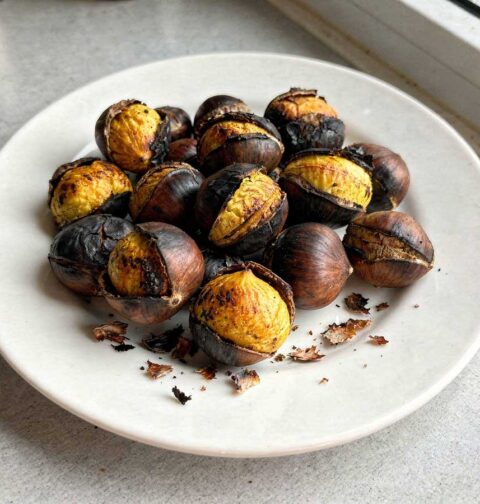 Een wit bord met daarop een portie geroosterde tamme kastanjes.