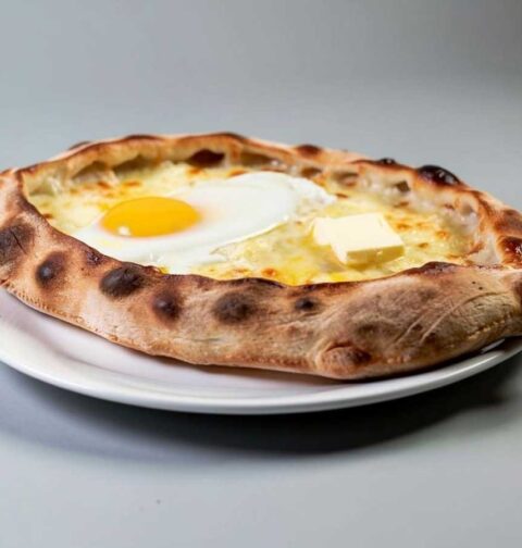 Een hele khachapuri op een wit bord.