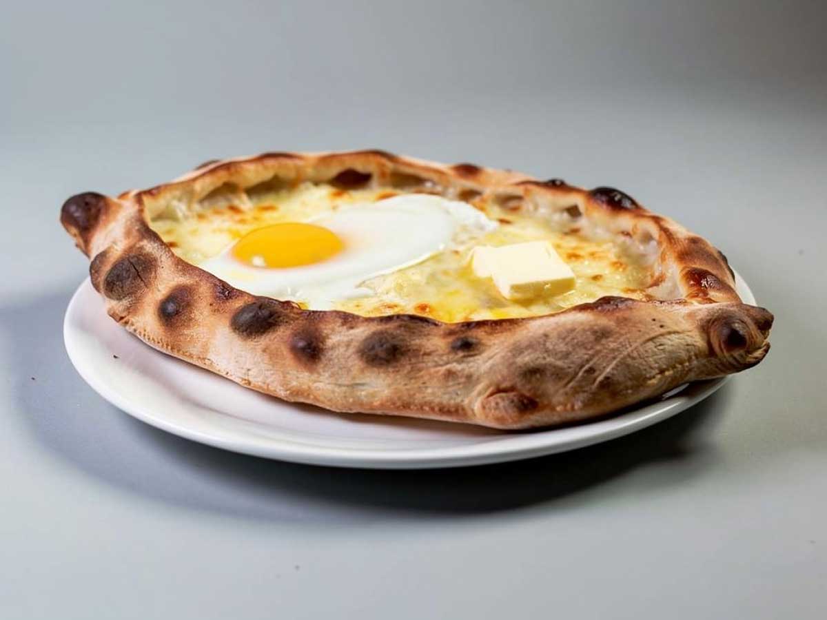 Een hele khachapuri op een wit bord.