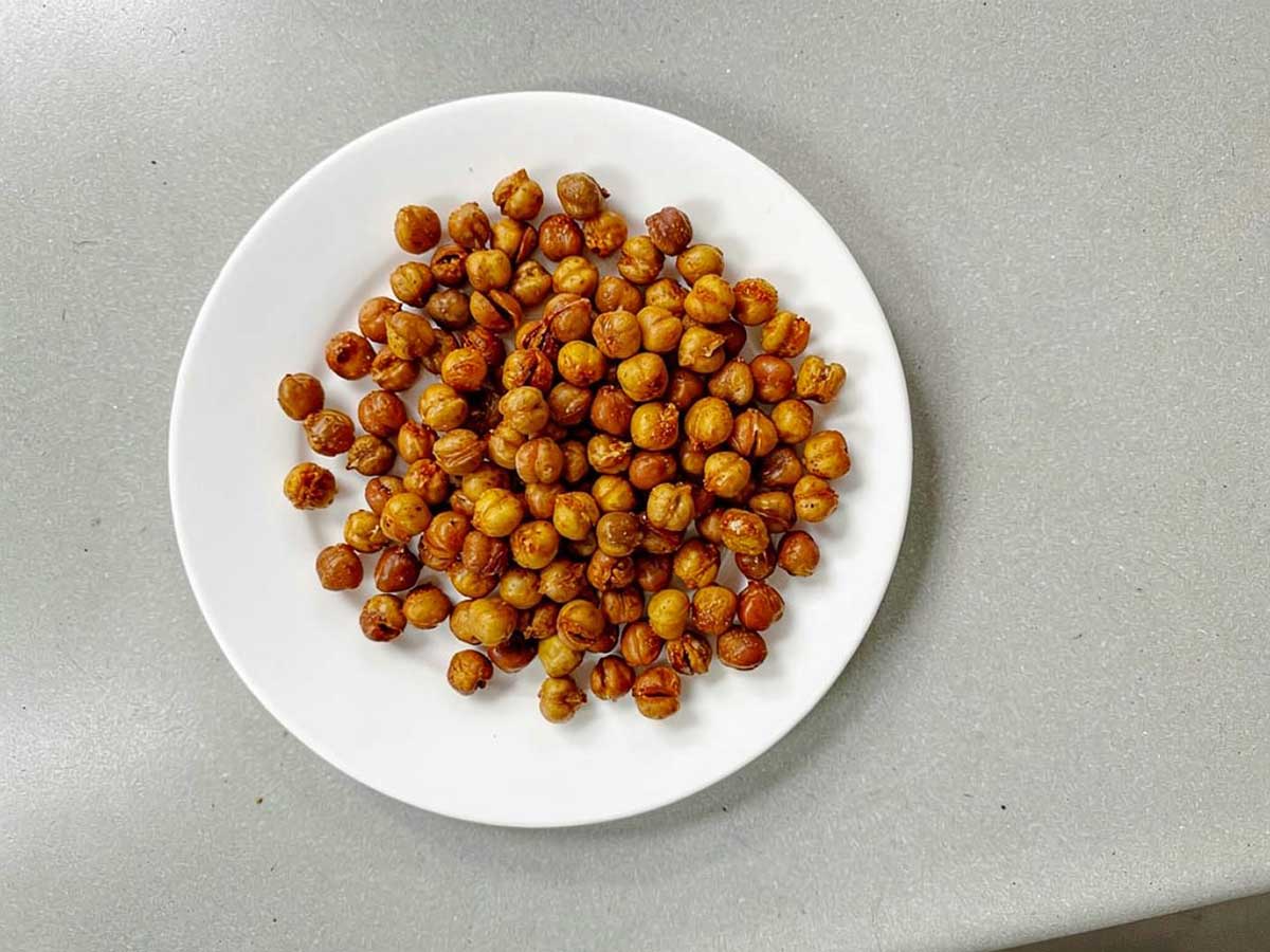 Een wit bord met daarom een portie geroosterde kikkererwten.