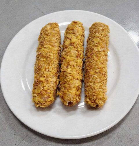 3 gefrituude kipcorn liggen op een wit bordje.