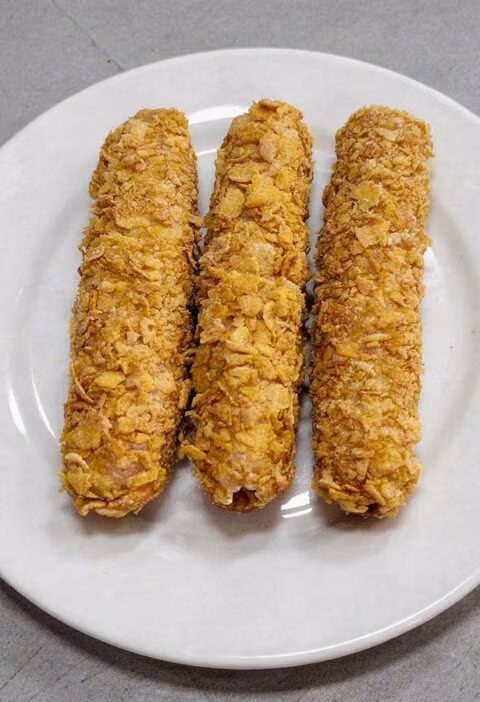 3 gefrituude kipcorn liggen op een wit bordje.