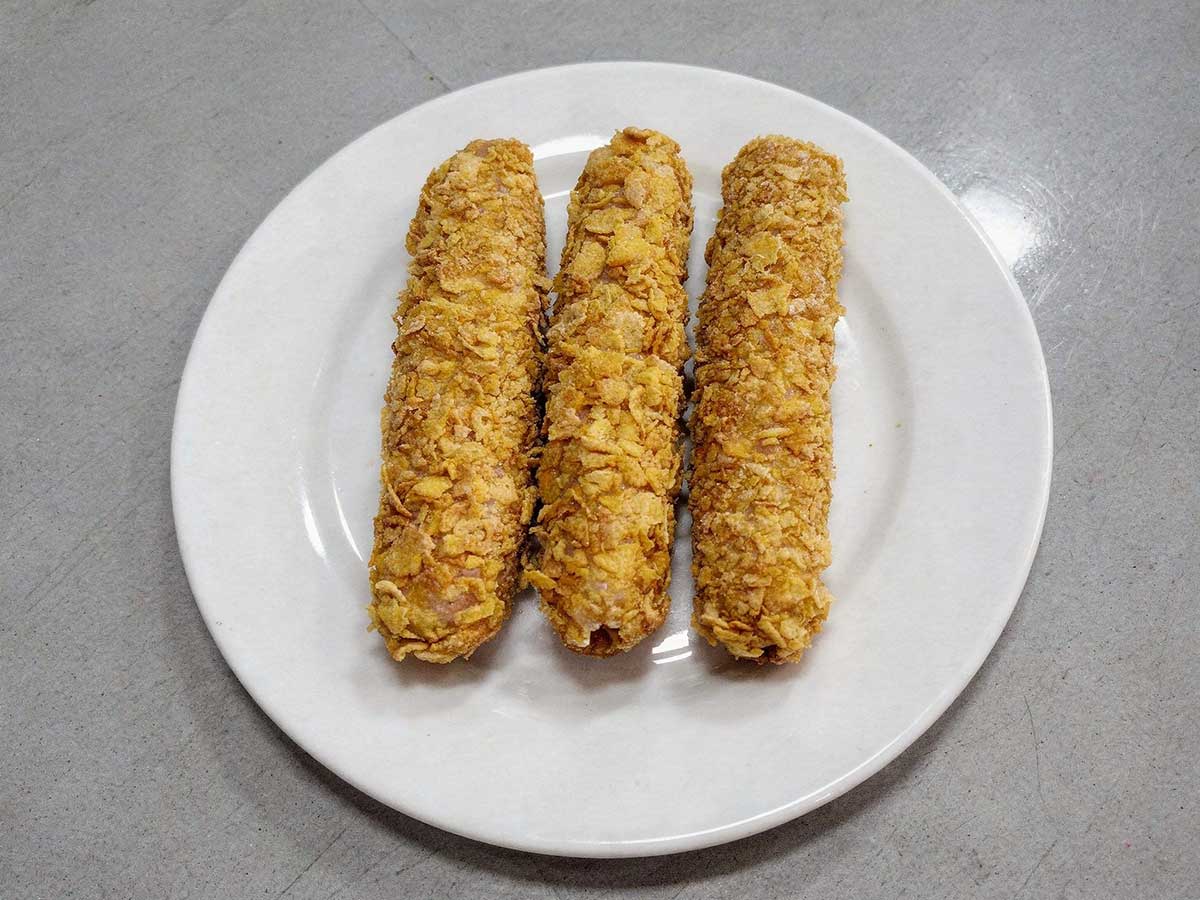 3 gefrituude kipcorn liggen op een wit bordje.