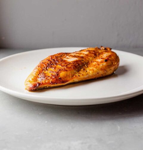 Een heerlijk gebakken kipfilet op een wit bord.