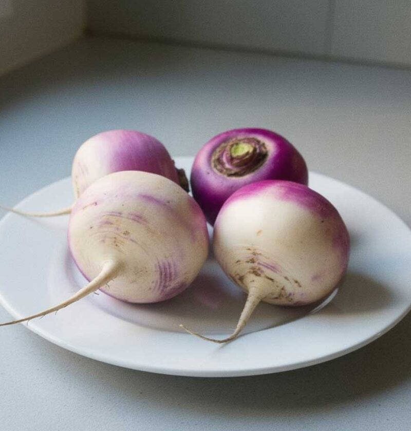 4 knolrapen zonder loof op een wit bord.