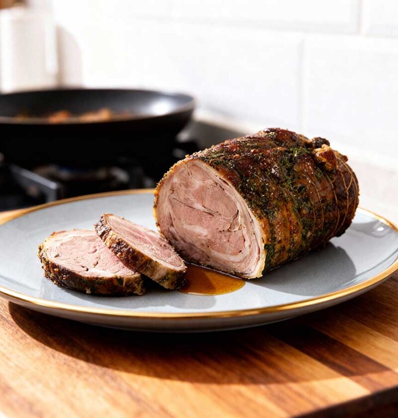 Een gebraden lamsrollade op een grijze schaal.