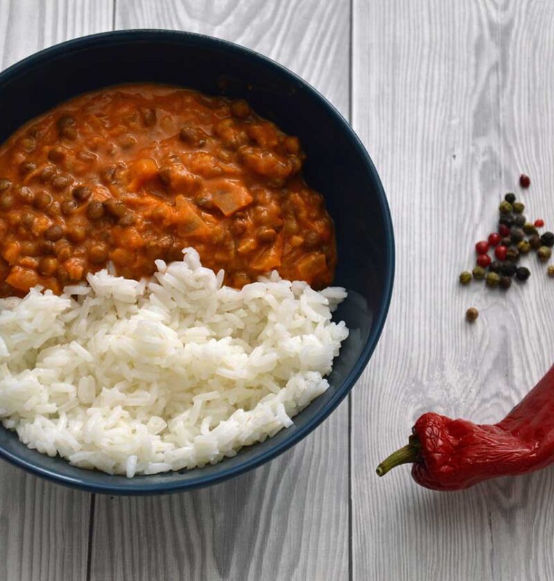 Linzencurry met rijst in een blauw schaaltje met allerlei pepers.