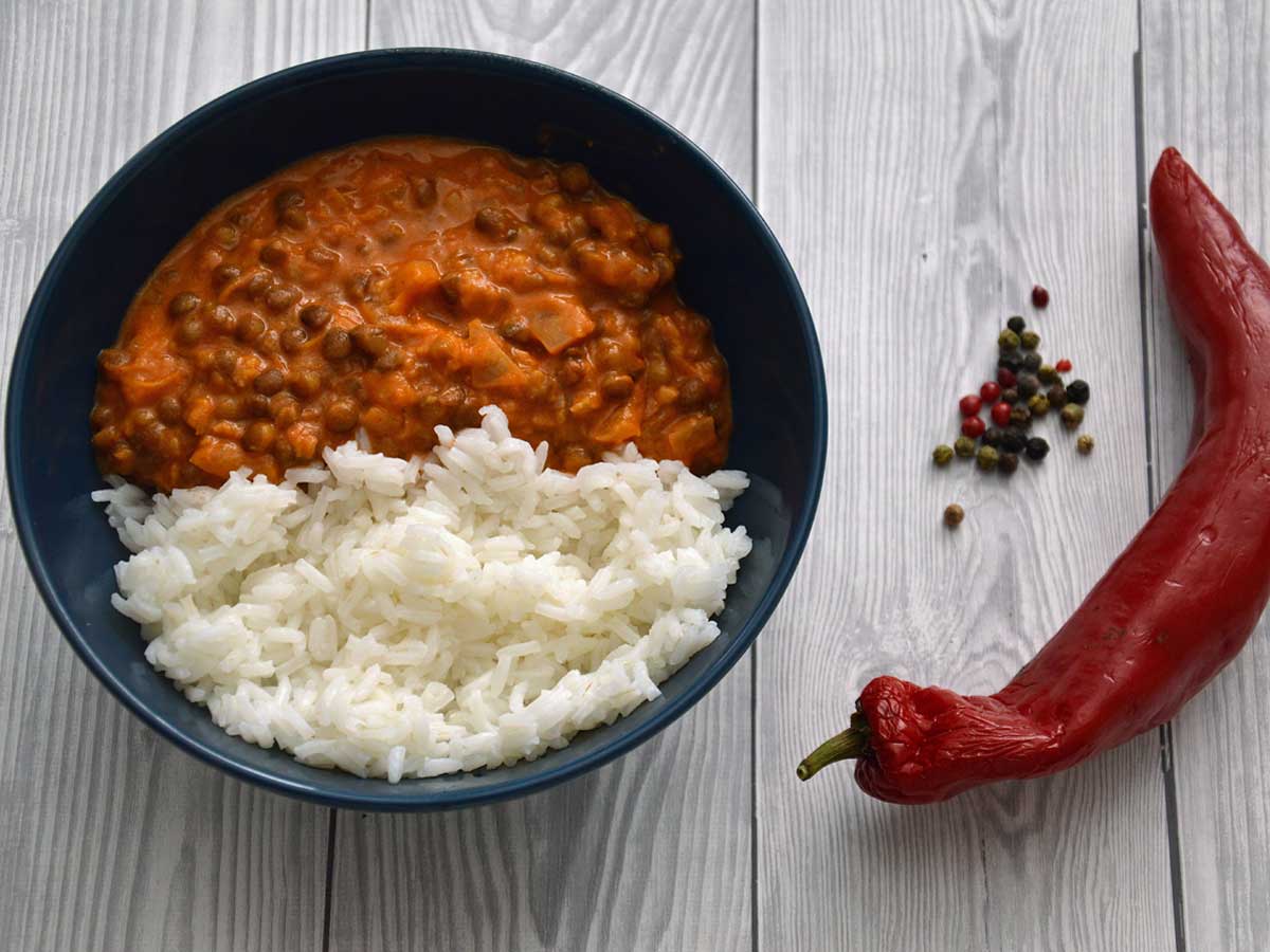 Linzencurry met rijst in een blauw schaaltje met allerlei pepers.