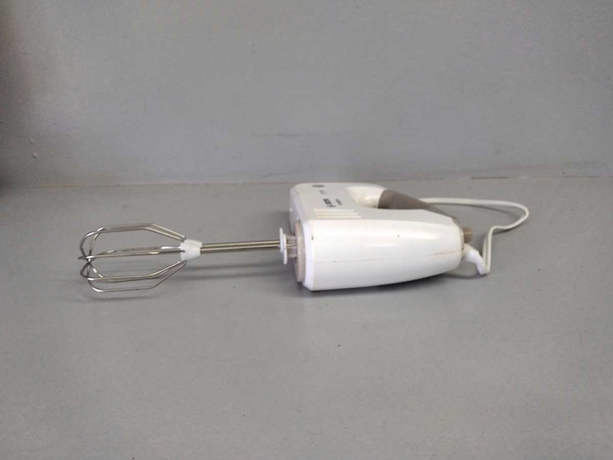 Een schone handmixer ligt op een werkblad.