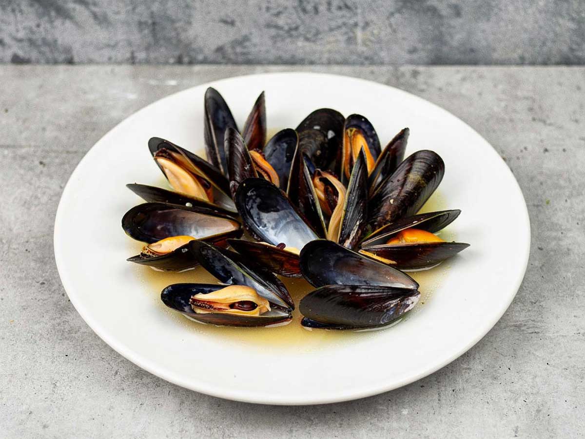 Een bord met gekookte mosselen en een beetje kookvocht.