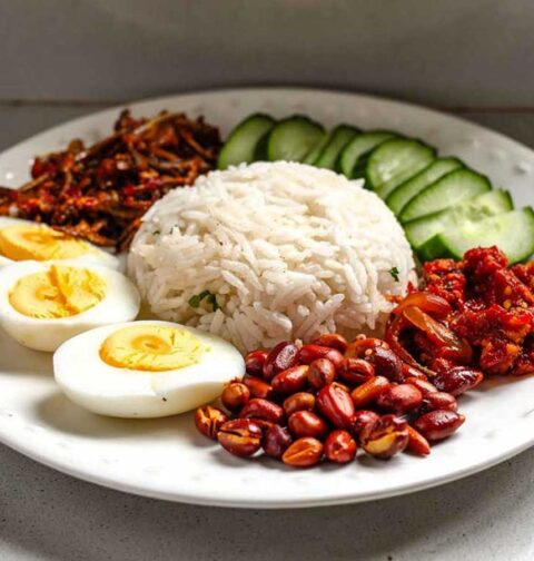 Een bord met nasi lemak, alle delen separaat.