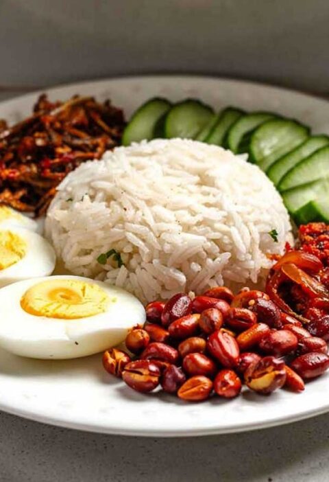 Een bord met nasi lemak, alle delen separaat.