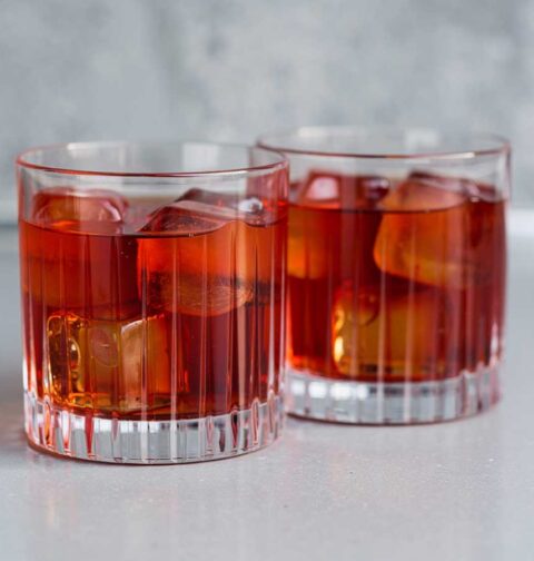2 glazen met negroni mocktail en ijsklontjes.