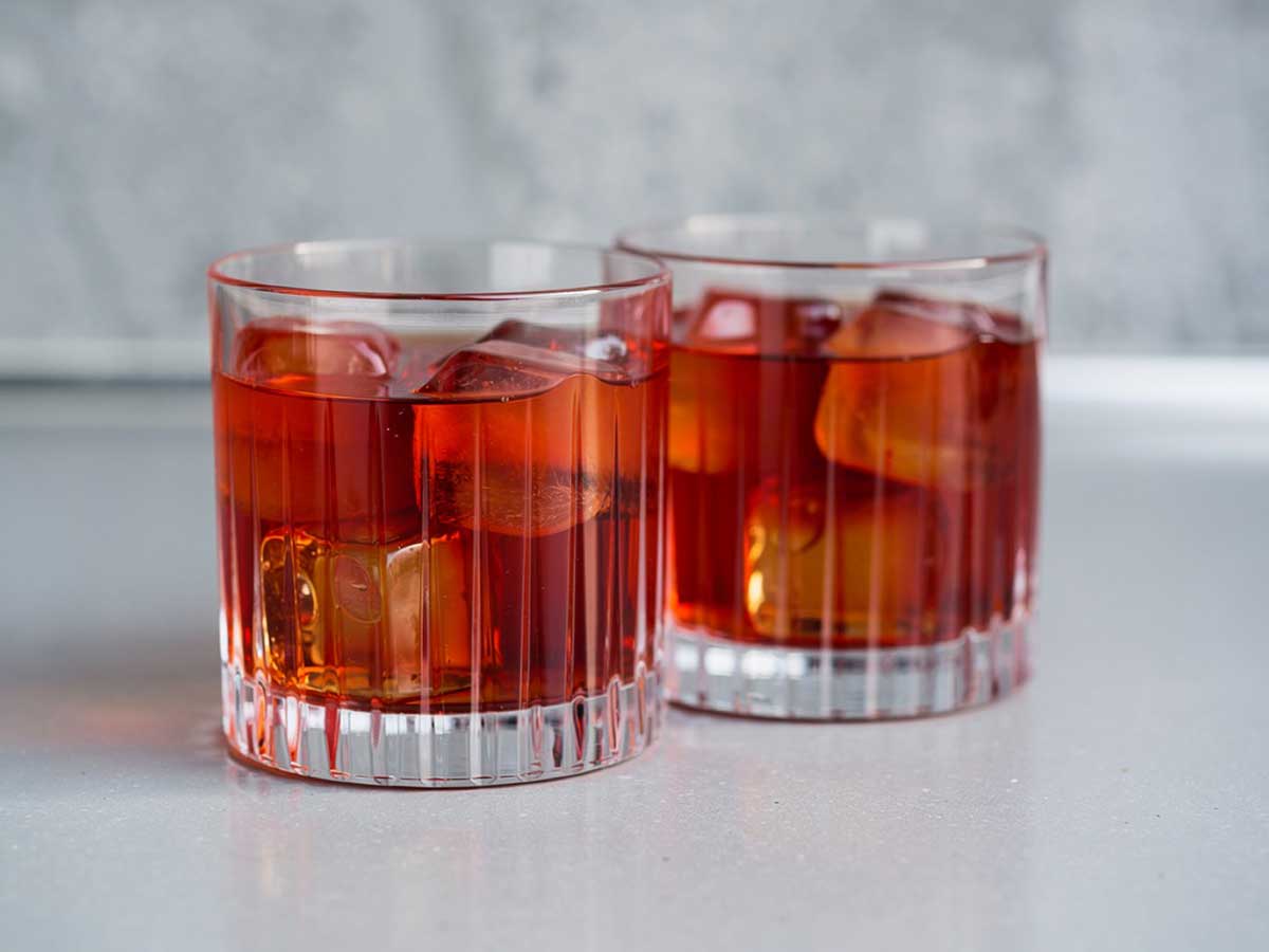2 glazen met negroni mocktail en ijsklontjes.