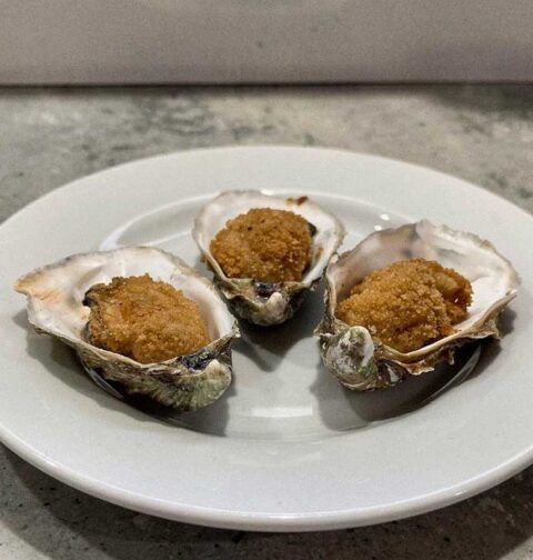 Drie gebakken oesters, teruggelegd in de schelpen.