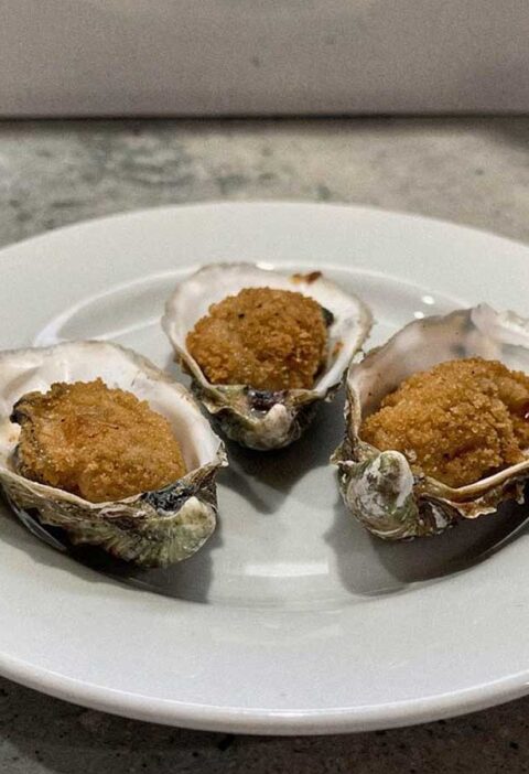 Drie gebakken oesters, teruggelegd in de schelpen.