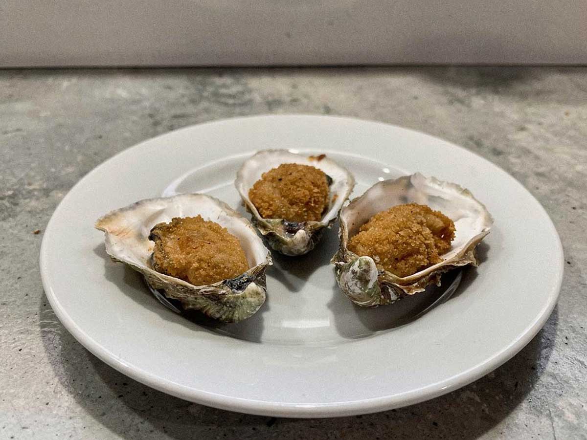 Drie gebakken oesters, teruggelegd in de schelpen.