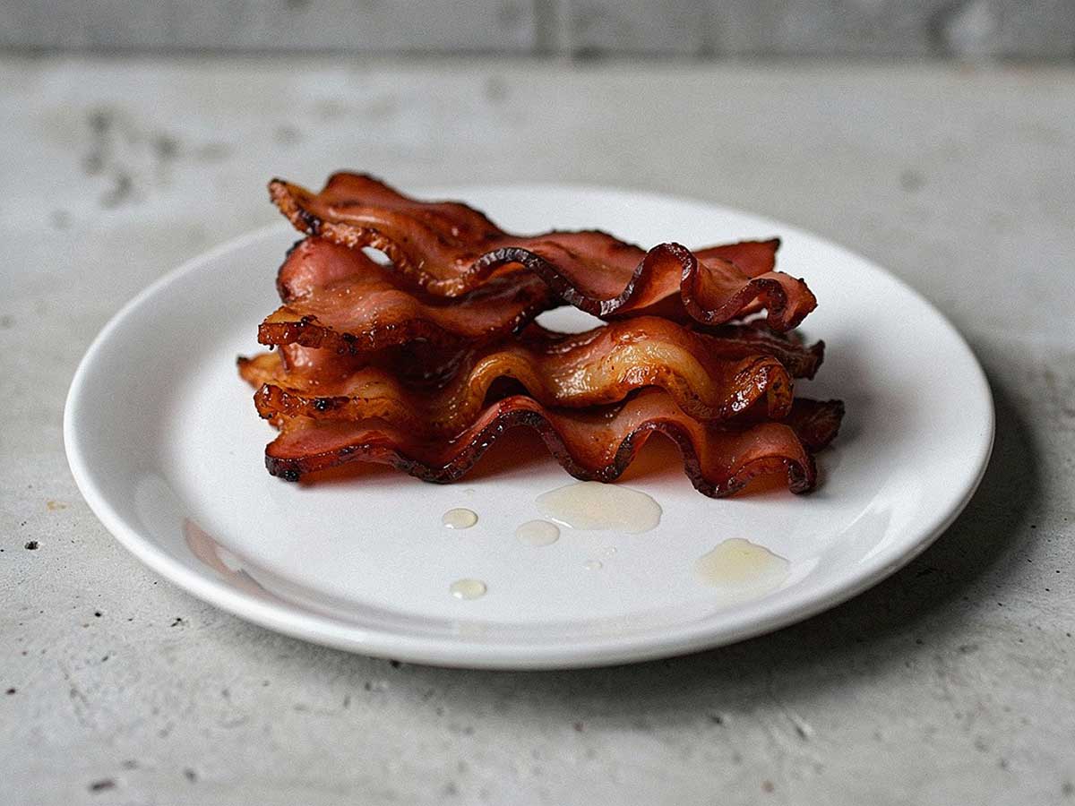 4 gebakken plakken pancetta op een wit bordje.