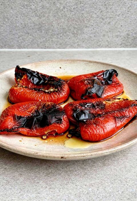 4 stukken geroosterde paprika op een bord.