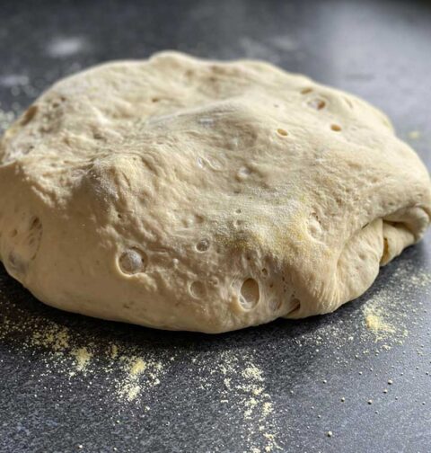 Een gerezen bol pastadeeg op een werkblad.