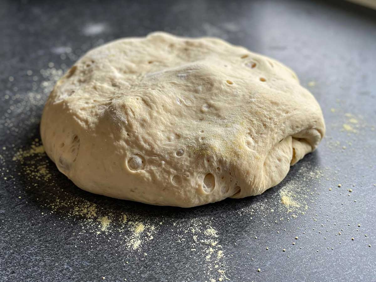 Een gerezen bol pastadeeg op een werkblad.