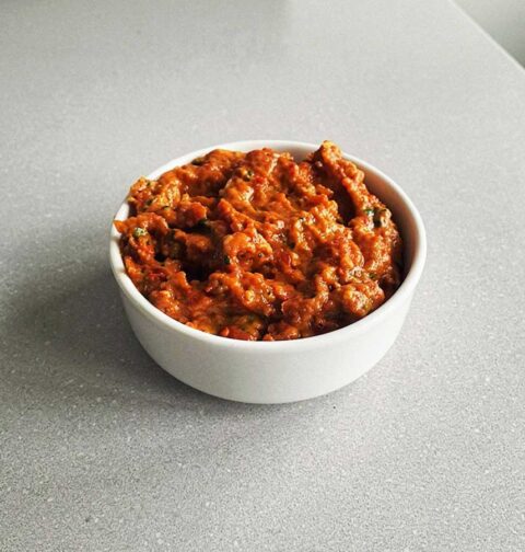 Een klein bakje met rode opgewarmde pesto.