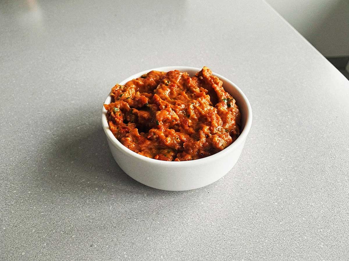 Een klein bakje met rode opgewarmde pesto.