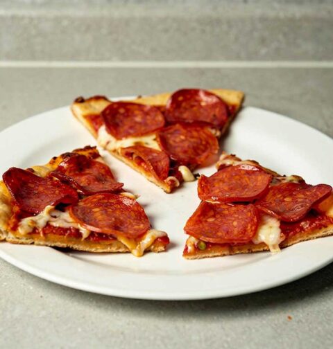 Drie stukken pizza salami die gebakken zijn op een BBQ.