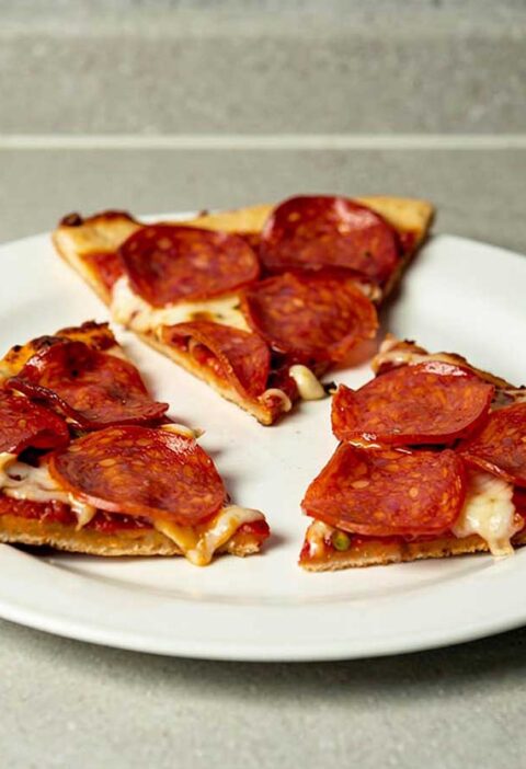 Drie stukken pizza salami die gebakken zijn op een BBQ.