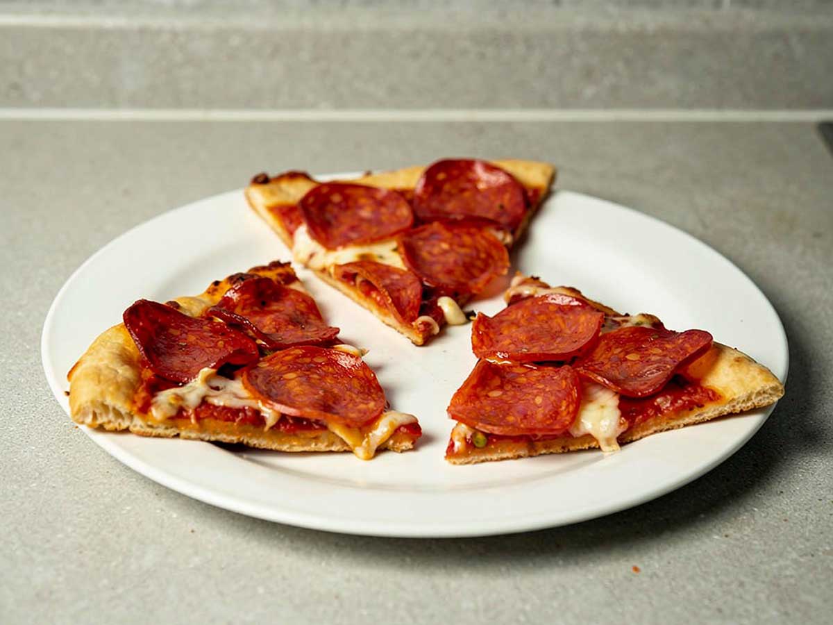 Drie stukken pizza salami die gebakken zijn op een BBQ.