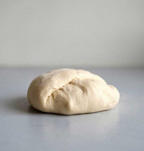 Een bol zelfgemaakt pizzadeeg, klaar om uit te rollen.