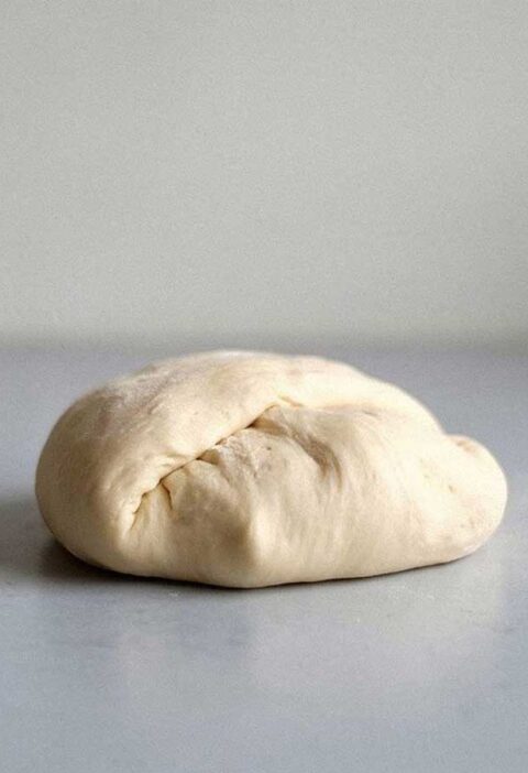 Een bol zelfgemaakt pizzadeeg, klaar om uit te rollen.