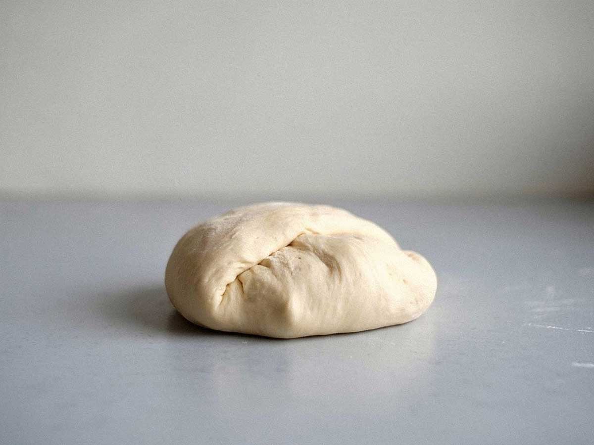 Een bol zelfgemaakt pizzadeeg, klaar om uit te rollen.