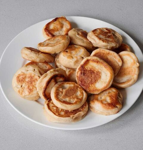Een bord met ogewarmde poffertjes.