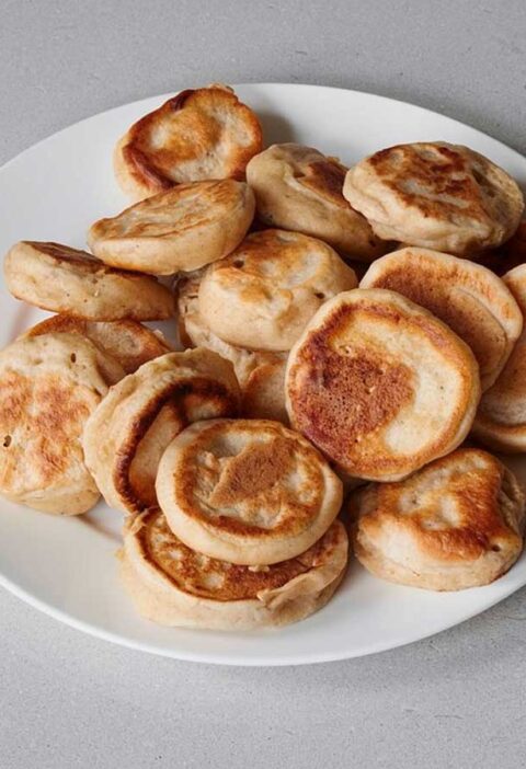 Een bord met ogewarmde poffertjes.