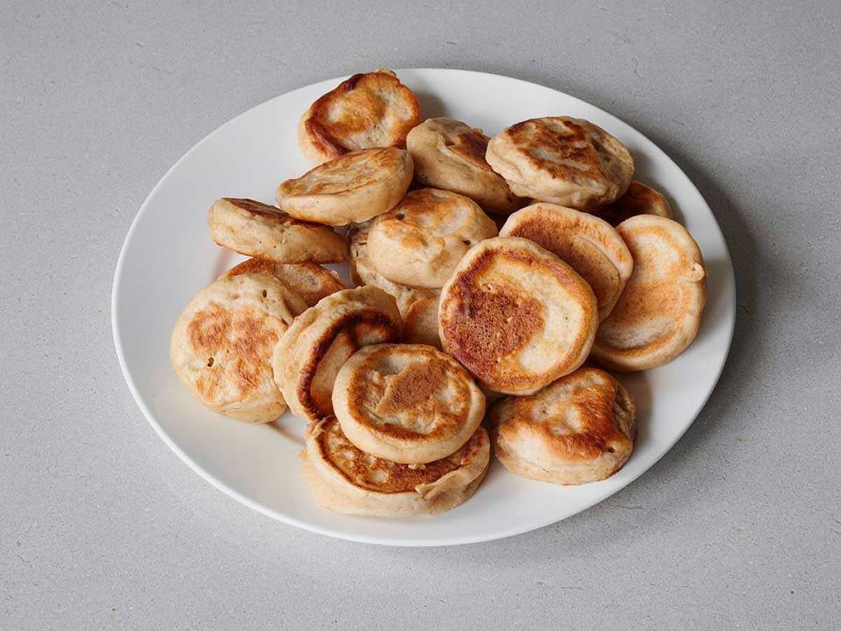 Een bord met ogewarmde poffertjes.