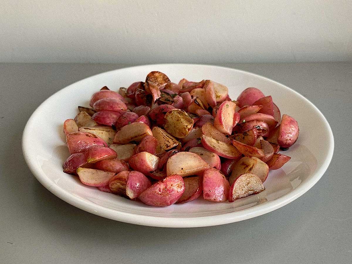 Een bordje met gebakken, meest gehalveerde, radijsjes.