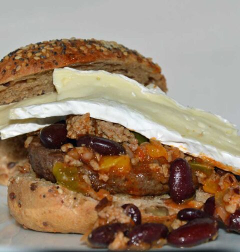 Een zacht broodje met daarop chili con carne en en paar plakken camembert.