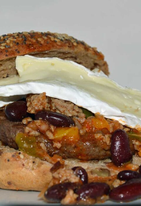 Een zacht broodje met daarop chili con carne en en paar plakken camembert.