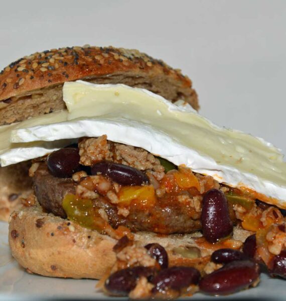 Een zacht broodje met daarop chili con carne en en paar plakken camembert.