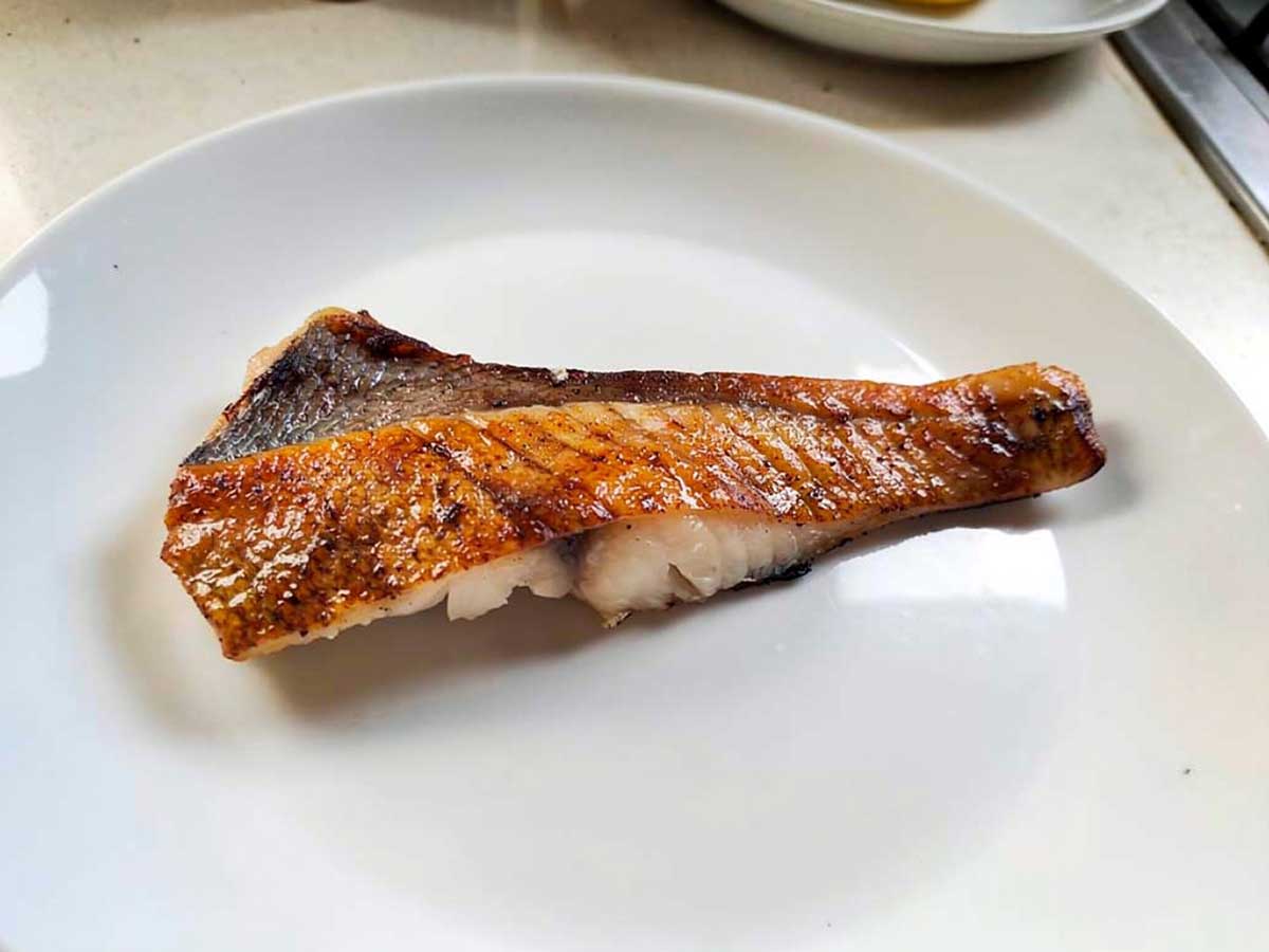 een gebakken red snapperfilet op een wit bordje.