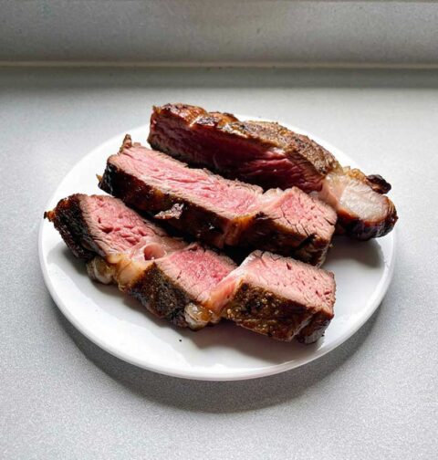 3 plakken ribeye, sommige met wat vet, liggen op een bord.