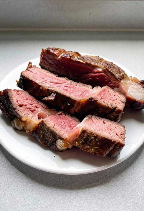 3 plakken ribeye, sommige met wat vet, liggen op een bord.